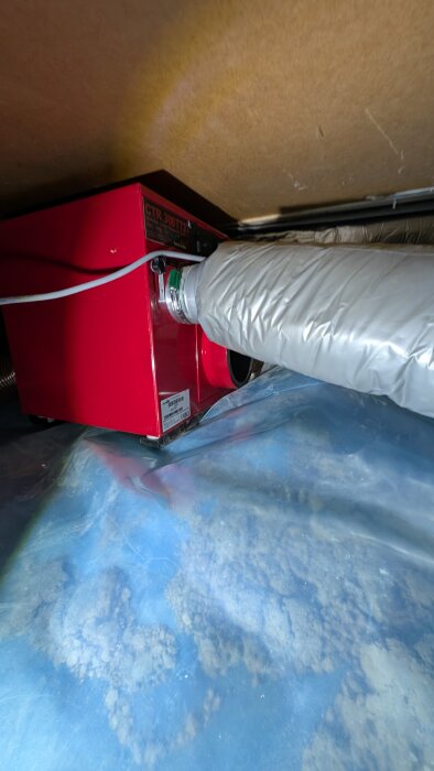 Corroventa 300tt2 installerad i krypgrund med ansluten ventilationsslang över plastfolie på marken.