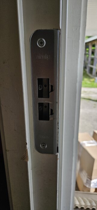 Närbild på ett nimly-lås monterat på en dörrkarm, visar ett olöst problem med att dörren inte är tät.
