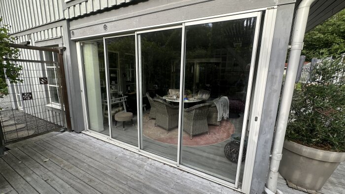 Skjutdörrar i glas från Willab Garden som vetter mot en terrass, med sittgrupp i rotting och matta synliga genom dörrarna.