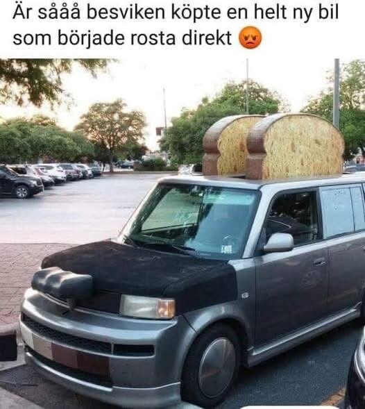 En bil på en parkeringsplats med två stora brödskivor ovanpå som ser ut som ett brödrostat motiv.
