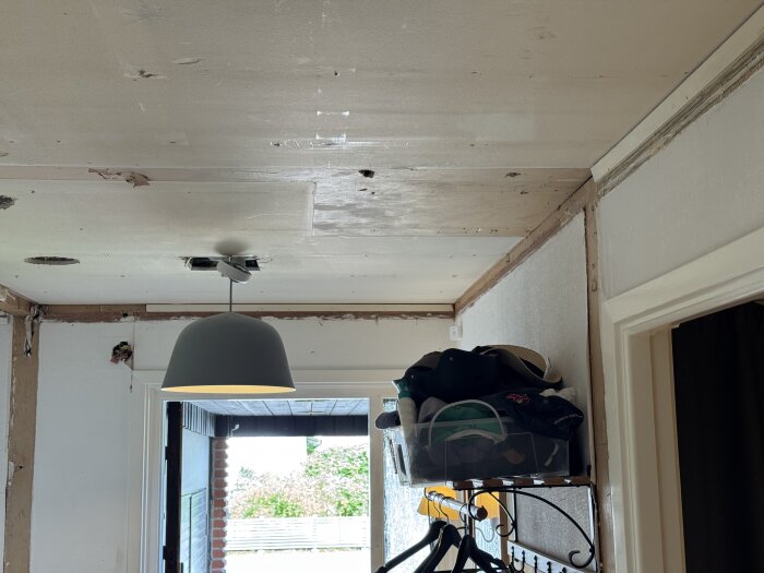 Tak med ny takdosa och gipsskivor som täcker hål från inbyggda dosor bredvid en lampa i en renoverad hall.