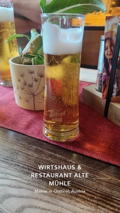 Glas med öl vid restaurangbord på Wirtshaus & Restaurant Alte Mühle i Matrei in Osttirol, Österrike.