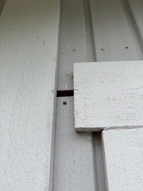 Glipa på vit trähusfasad nära fönsterbräda; detalj av bräda med mellanrum visar potentiellt problem med tätning.