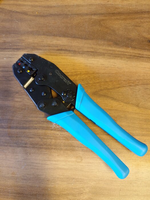 Kabelsko-tång från Cocraft med blå handtag, liggande på ett träbord.