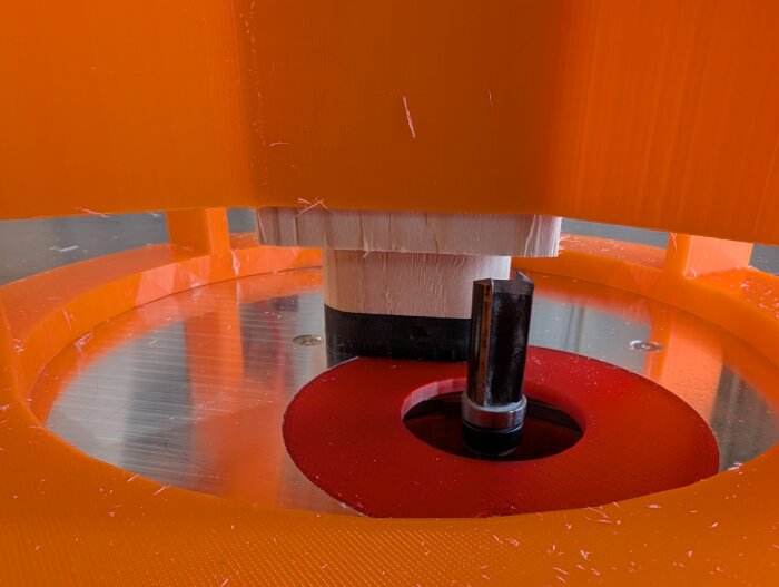 3D-utskrivet orange verktygshållare med metallfräs inuti, används för träarbeteskonstruktion i verkstad.