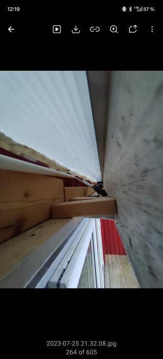 Takfot och panel utifrån ett uterum, delvis klädd och med synliga trädetaljer.