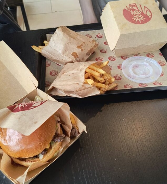 Hamburgare och pommes frites serverade på ett svart bord med Mr York-logotyp på förpackningarna.