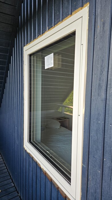 Nytt fönster monterat i blå fasad, visar glipor runt ramen där foder behövs.