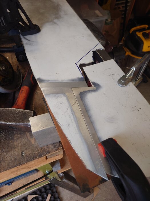 Aluminiumplåt med svets och slipad yta i en verkstadsmiljö, redo för bearbetning av instrumentpanel.