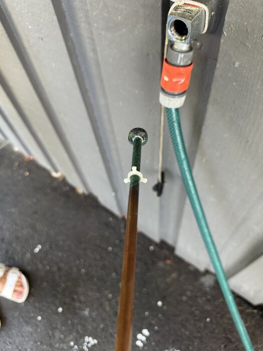 Frostsäkert vattenutkast demonterat från väggen, med en slang kopplad och intilliggande öppning synlig.