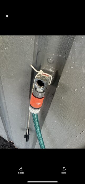 Frostsäker vattenutkastare med slang är lös; koppling synlig, fastbunden med snöre.