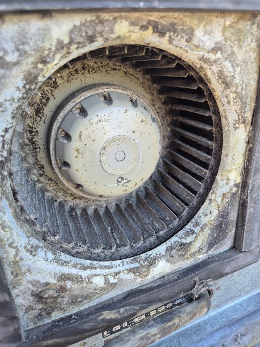 Smutsig köksfläkt före rengöring, med täckt fläktkåpa och dammiga blad.