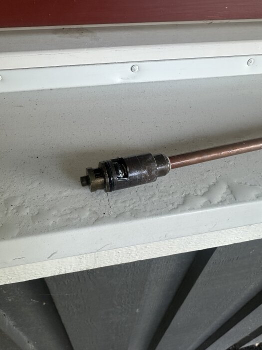 Munstycke på plasthuvud, kopplat till en kopparrör, liggande på en vit yta med en diskret bakgrund.