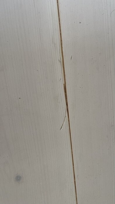 Glipa och skador i massivt furugolv i vardagsrum, nyligen installerat under fuktig period.