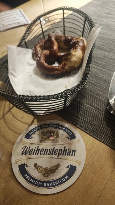 Korg med en pretzel på bord med Weihenstephan underlägg; restaurangbesök nära Autobahn.