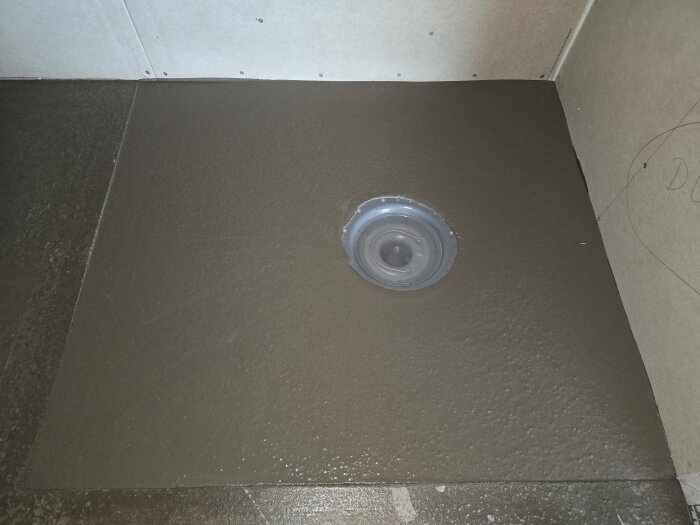 Golv med flytspackel runt brunnen med avstängningslist borttagen och jämnt fall mot brunnsflänsen.