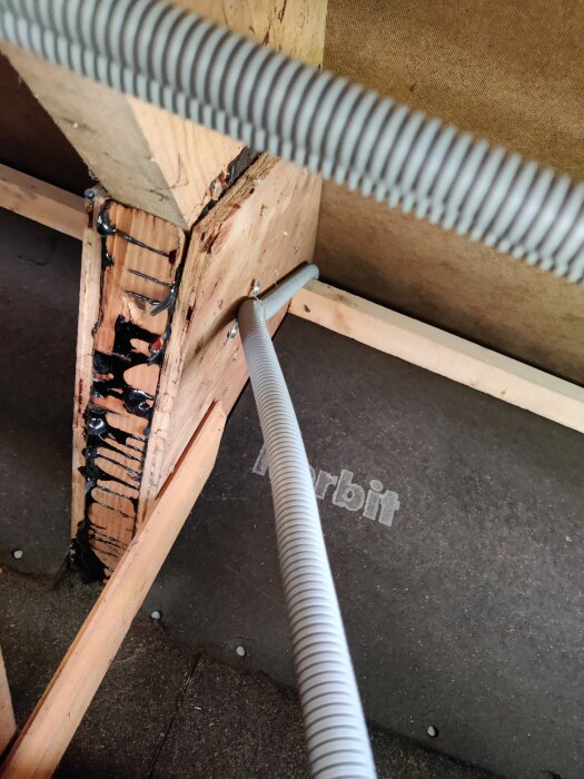 Flexslang installerad i takfoten för övervakningskameror, omgiven av trästruktur och isoleringsmaterial.