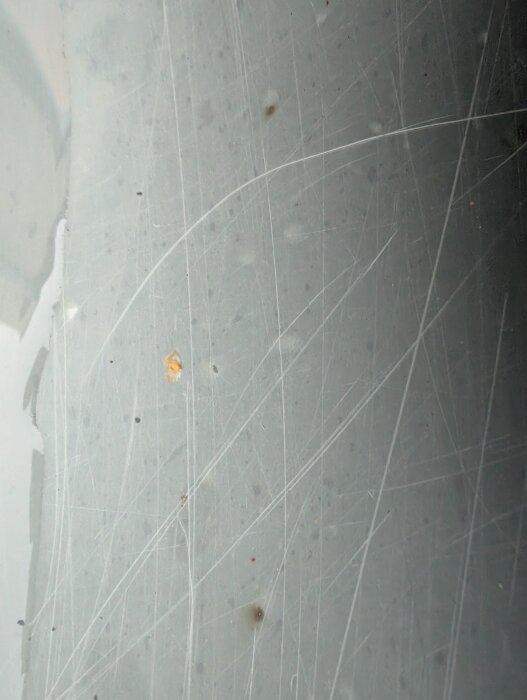 Bilden visar en närbild av glasfiberytan på ett utespa med bruna fläckar och små bubblor.