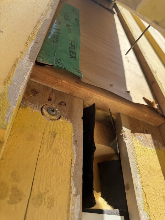 Bild av fasad med lockpanel, avslöjar underliggande vindpapp och trästruktur. Monteringsdetaljer och ytskikt i närbild.