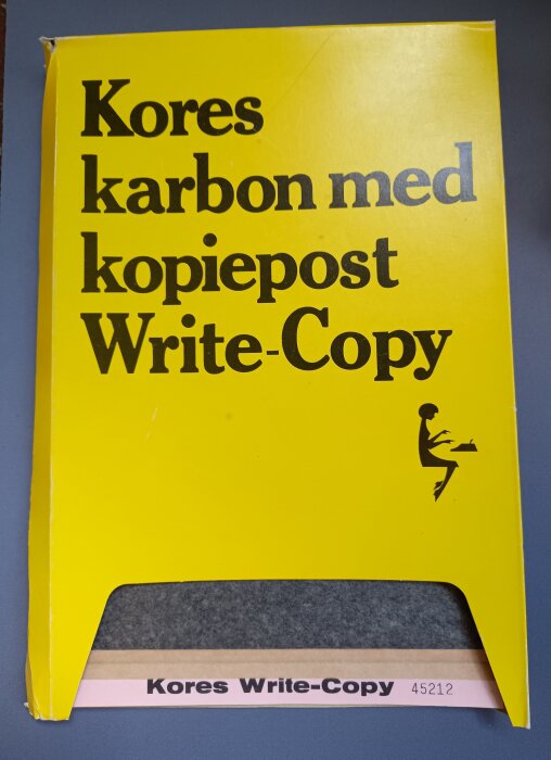 Förpackning med Kores karbonpapper, gul framsida med texten "Kores karbon med kopiepost Write-Copy" och en silhuett av en skrivande person.