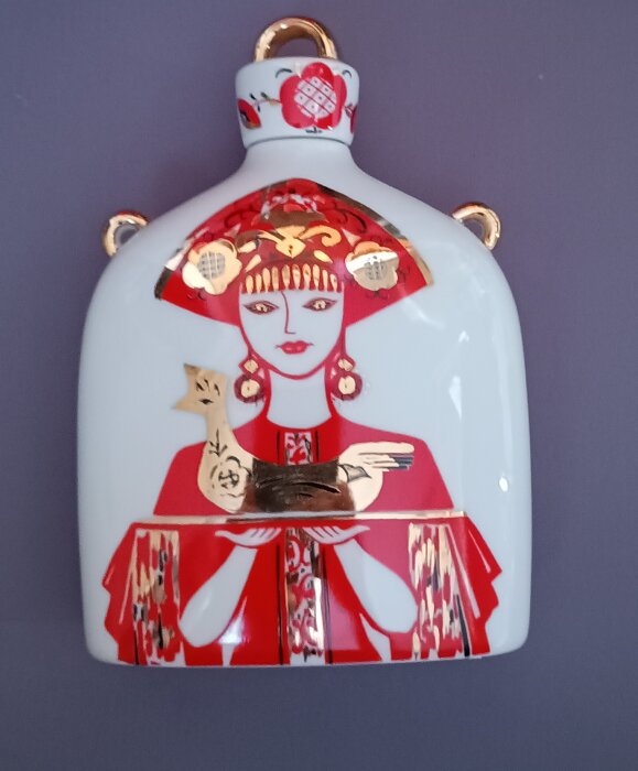 Karaff från Lomonosov med röd och vit illustration av en kvinna i traditionell klädsel, håller en brun fågel.