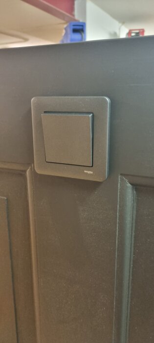 Svart ljusströmbrytare monterad på en ombyggd och målad dörr som används som sänggavel.