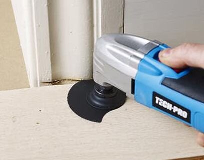 Person använder ett elektriskt verktyg för att såga i dörrfodret vid golvet.