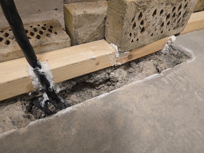 Form för gjutning av innervägg byggd med trä och tegelstenar, elslangar synliga genom skum, förberedd för betong.