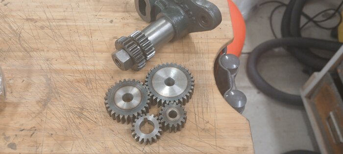 Metallkugghjul på en träbänk, del av ett svarvprojekt för millimetergänga, synliga repor på ytan.