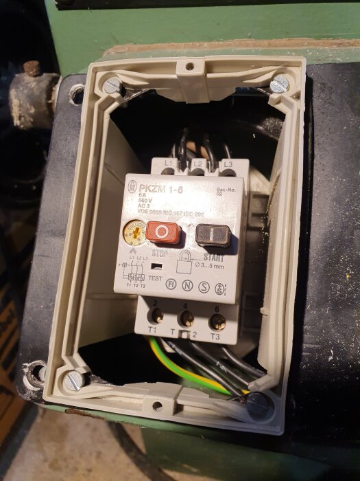 Motorskyddsbrytare PKZM 1-6 i öppet plasthölje med kablar och skruvanslutningar, sedd i närbild ovanifrån.