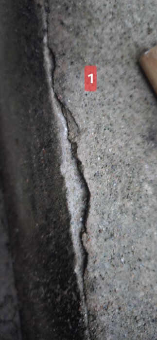 Spricka i betongtrappa markerad med nummer 1, visar slitage och behov av reparation.