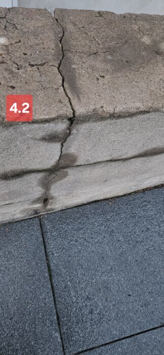 Spricka i betongvägg ovanför svart stenbeläggning, identifierad som bild 4.2.