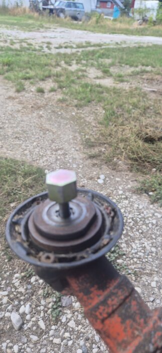 Närbild på en röjsågs vinkelväxel med en bult och flera brickor monterade där en trimmerspole tidigare suttit.