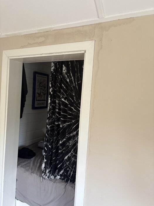 En vägg med ljusa fläckar ovanför en dörröppning, misstänkt som fukt, i en kolonistuga.