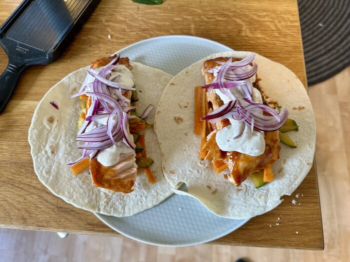 Laxwraps med teriyakisås, färska grönsaker och rödlök på en tallrik, öppna och rikligt fyllda.