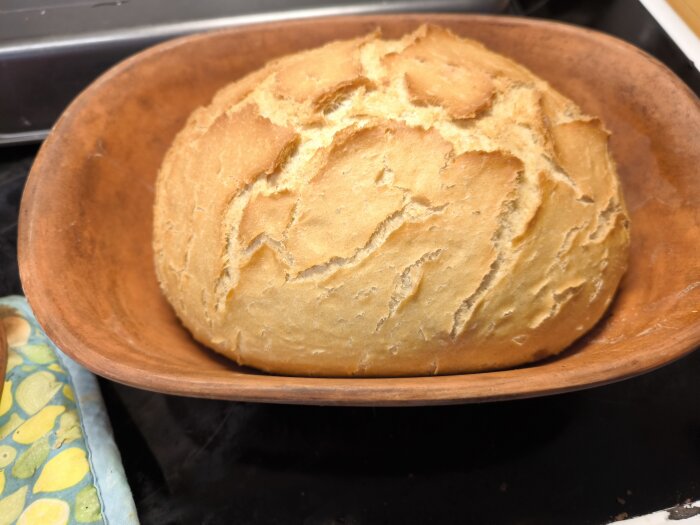 Grekiskt lantbröd bakat i lergryta, gyllenbrun skorpa, i ett kök.