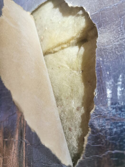 Isolering med reflekterande yta och gul isoleringsmaterial under skikt.