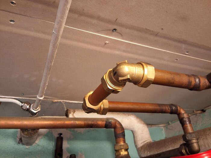 Kopparrör med kopplingar under tak, anslutna med stödhylsor. Rören är kapade och gradade, installerade i ett byggprojekt.