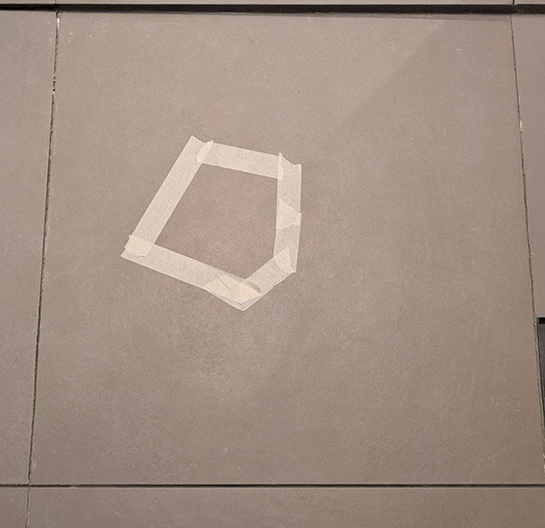 Klinkerplatta i dusch med markerad yta med tejp där bomljud uppstår, risk för läckage ifrågasätts.