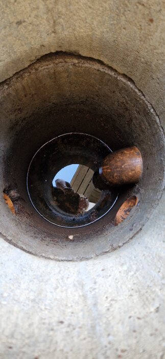 Insidan av en rensbrunn med synligt vatten, rör och betongväggar. Brunnen används för dagvattenhantering.