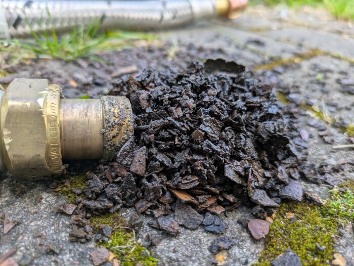 Flexslang med korroderat material på marken efter rengöring av värmepumpens värmeväxlare.