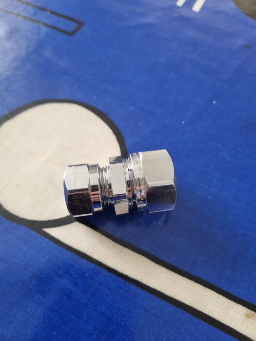 En metallkoppling ligger på en blå yta.