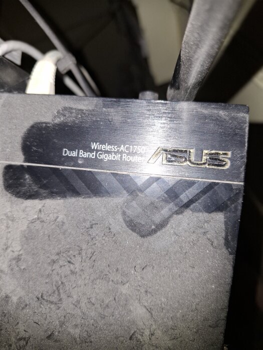 En svart Asus Wireless-AC1750 Dual Band Gigabit Router med dammlager, placerad högt.