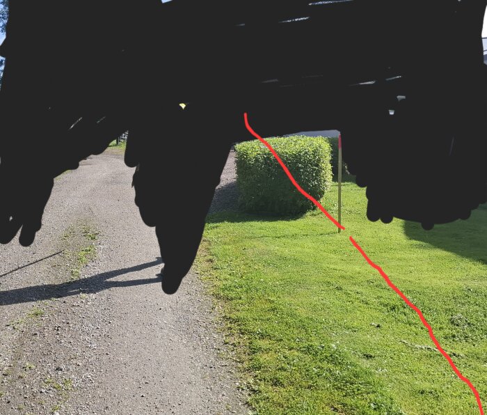 Grusväg och gräsmatta med röd linje som markerar en tänkt gräns.