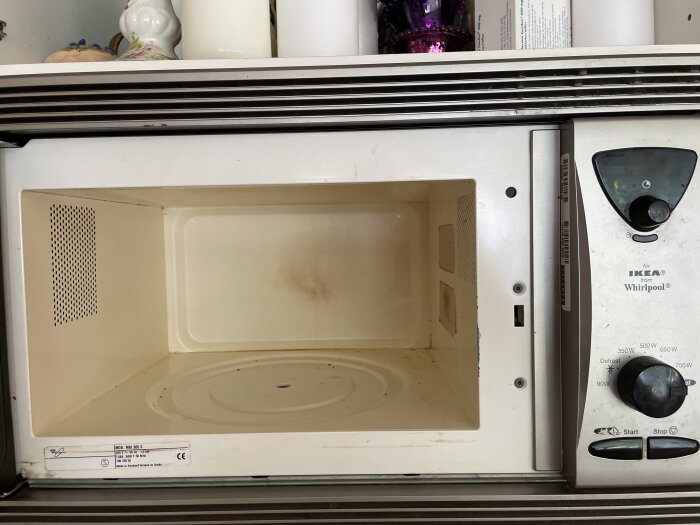 Öppen mikrovågsugn från IKEA och Whirlpool med synlig roterande platta och kontrollpanel på höger sida.