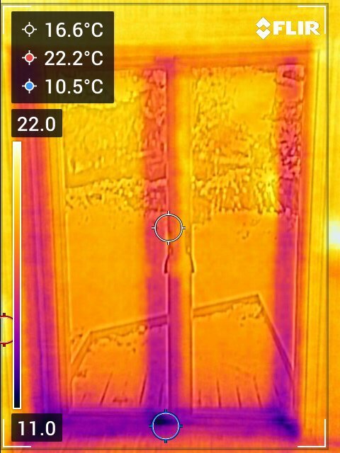 Termobild av altandörr som visar temperaturvariationer; kallare vid golvet och varmare högre upp, med olika färger indikerande temperaturskillnader.