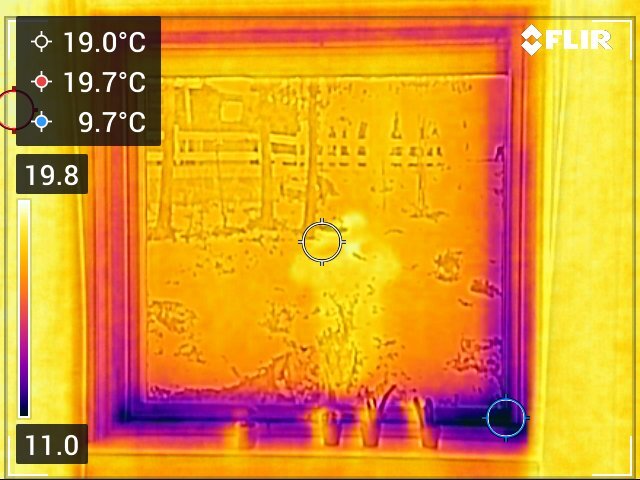 Värmekamera visar temperaturvariationen runt ett fönster med isoleringsproblem; varmare inomhus och svalare längs kanter. Temperaturen varierar mellan 9,7°C och 19,7°C.