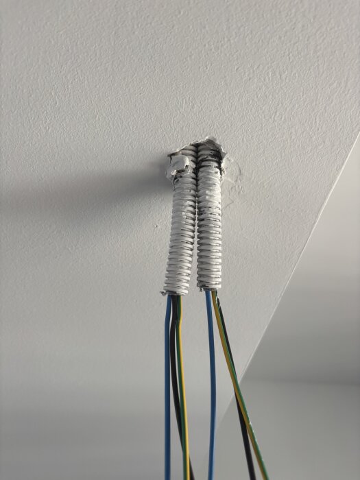 Elledningar genom tak i nybyggd lägenhet i Spanien, redo för installation av spotlights. Två elrör med kablar är synliga genom ett hål.