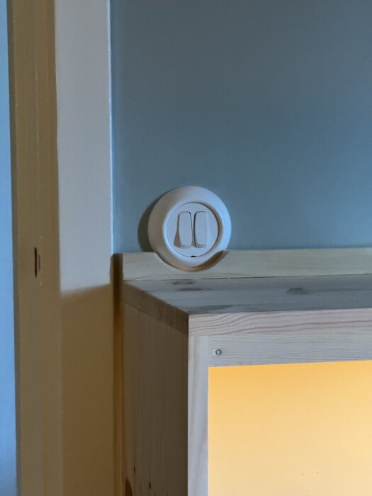 Väggströmbrytare ovanför ett hemmagjort skrivbord med ett integrerat hyllplan och lampa i sonens rum.