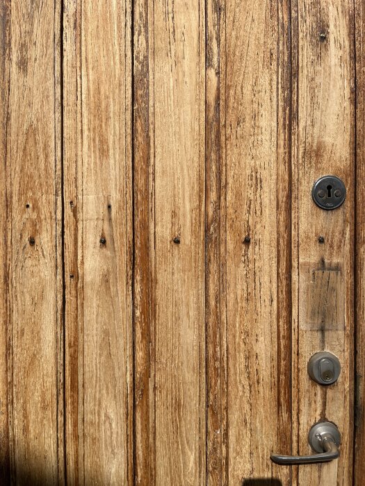 Dörr i teak från 60-talet med synliga oljerester och låsdetalj.